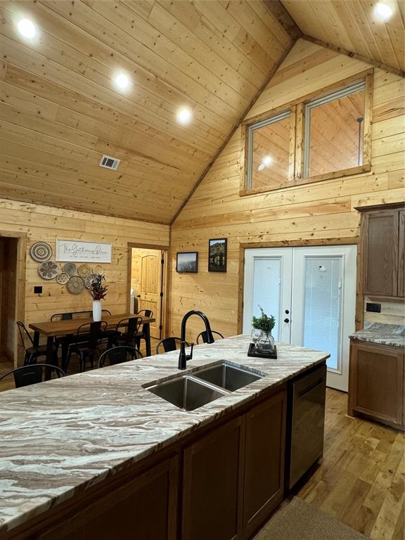 kitchen with wooden walls, sink, light hardwood / wood-style flooring, wooden ceiling, and lofted ceiling