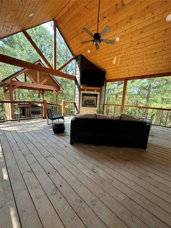 deck featuring an outdoor stone fireplace and ceiling fan