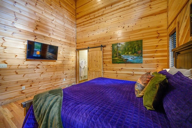 bedroom featuring hardwood / wood-style floors, wooden walls, and a high ceiling