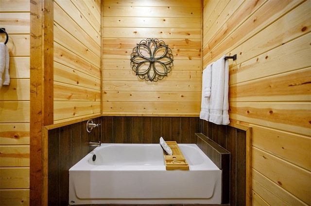 bathroom featuring wooden walls and a bath