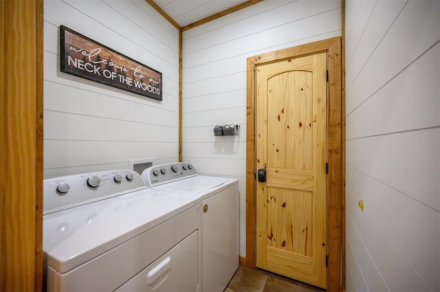 clothes washing area with washing machine and dryer and wooden walls