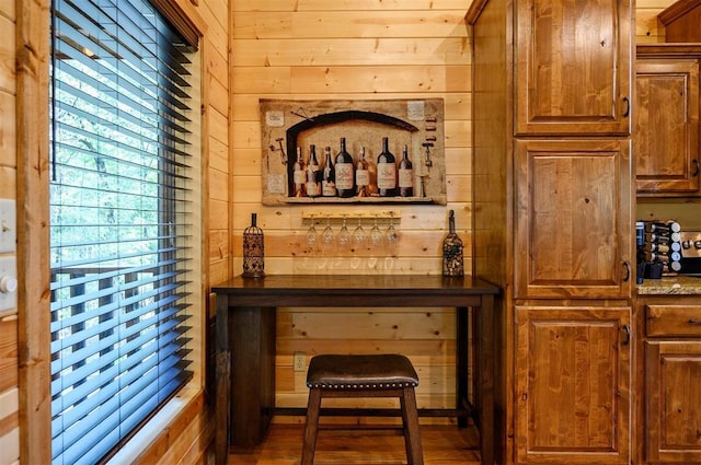 wine cellar with bar, wooden walls, and wood-type flooring