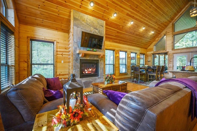 living room featuring wood walls, wood ceiling, a fireplace, and high vaulted ceiling