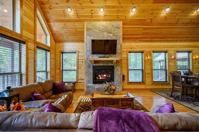 living room with hardwood / wood-style floors, a stone fireplace, lofted ceiling, and wooden ceiling