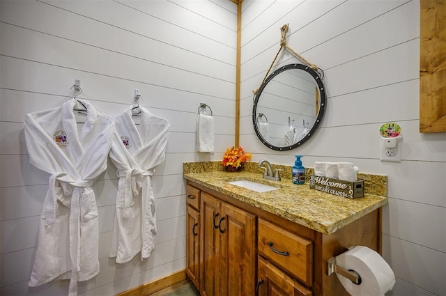 bathroom featuring vanity and wood walls