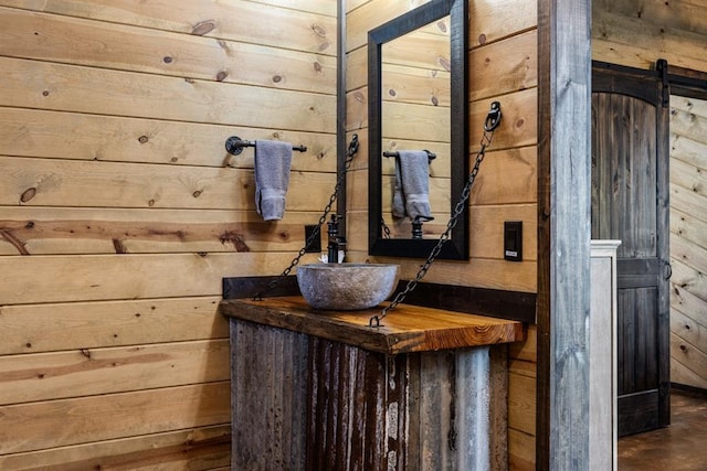 interior space with a barn door, wood walls, and sink