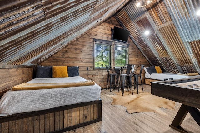 bedroom featuring lofted ceiling, light wood-type flooring, and wooden walls