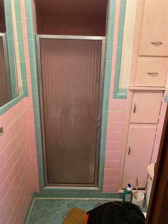 bathroom with tile patterned flooring, a shower with shower door, and tile walls