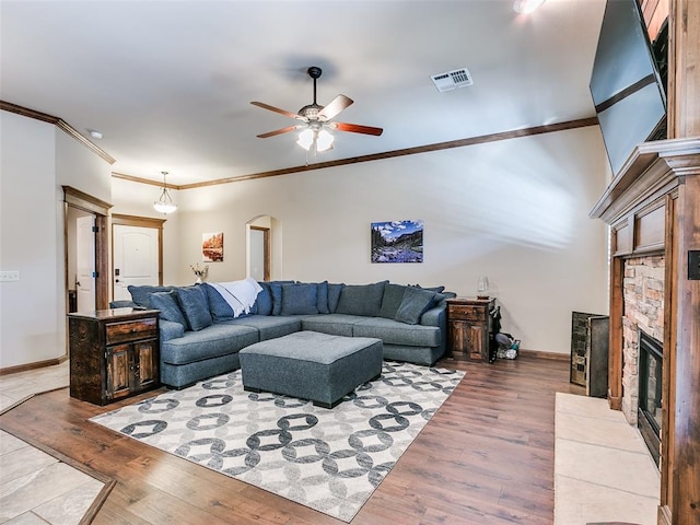 living room featuring ceiling fan, a fireplace, light wood-type flooring, and ornamental molding