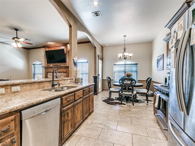 kitchen featuring light stone countertops, sink, decorative light fixtures, ceiling fan with notable chandelier, and appliances with stainless steel finishes