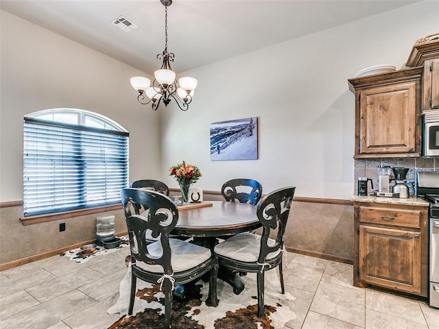 tiled dining room featuring lofted ceiling and a notable chandelier