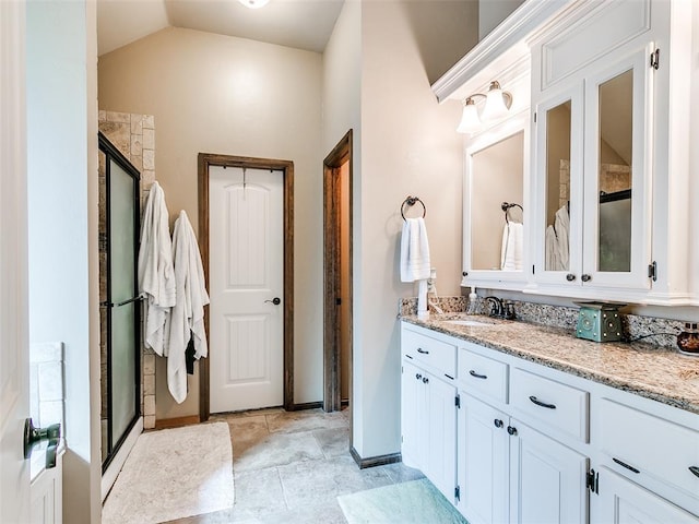 bathroom with vanity, a shower with door, and vaulted ceiling