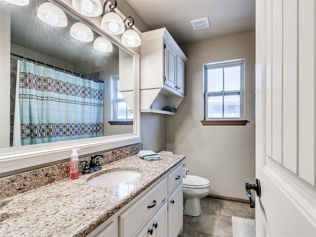 bathroom with tile patterned floors, vanity, a healthy amount of sunlight, and toilet