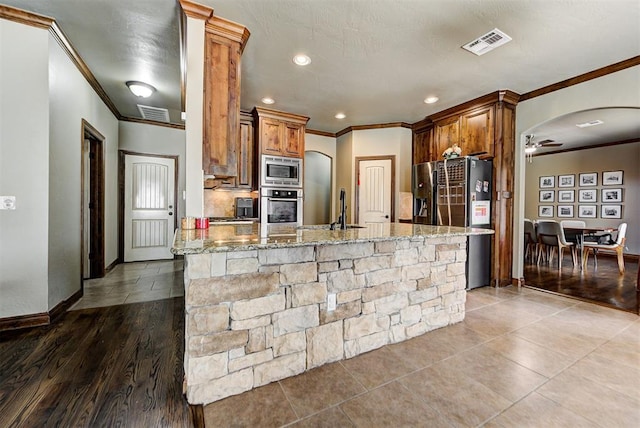 kitchen featuring crown molding, sink, light stone countertops, appliances with stainless steel finishes, and wood-type flooring