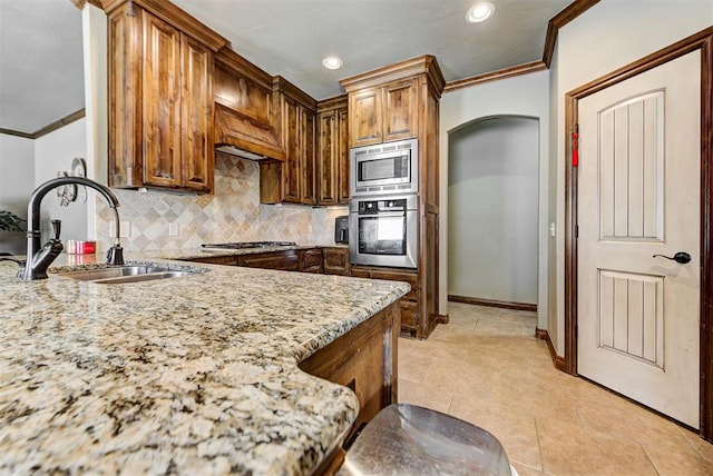 kitchen with sink, decorative backsplash, ornamental molding, light stone counters, and stainless steel appliances