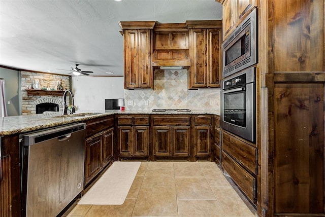 kitchen with light stone countertops, sink, ceiling fan, stainless steel appliances, and light tile patterned flooring