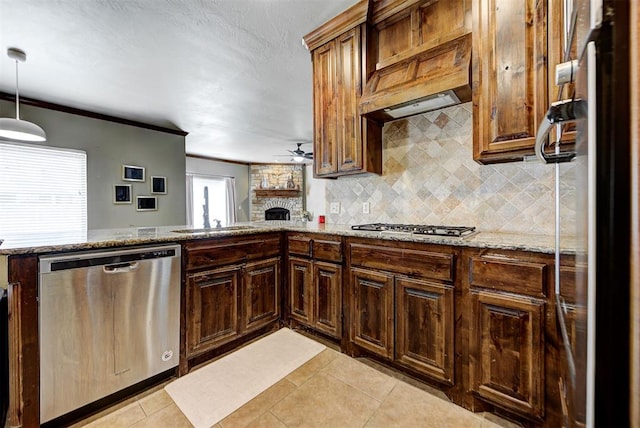 kitchen featuring light stone countertops, stainless steel appliances, ceiling fan, sink, and pendant lighting