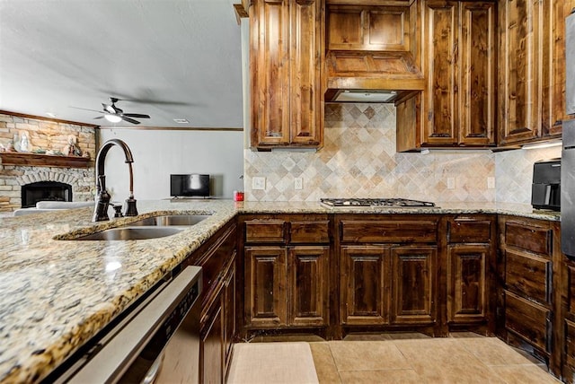 kitchen with sink, ceiling fan, light stone countertops, a fireplace, and stainless steel appliances