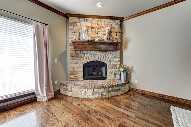 unfurnished living room with a stone fireplace, crown molding, and wood-type flooring