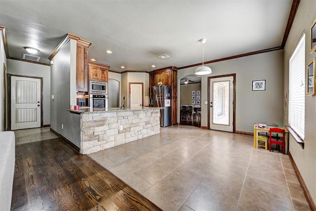 kitchen featuring ceiling fan, dark wood-type flooring, light stone counters, kitchen peninsula, and appliances with stainless steel finishes