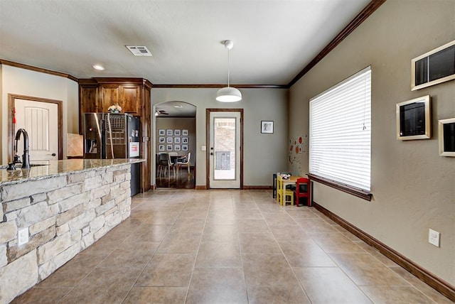 kitchen with light stone countertops, sink, stainless steel fridge with ice dispenser, decorative light fixtures, and light tile patterned floors