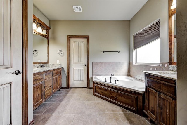 bathroom with tile patterned flooring, vanity, and a bath