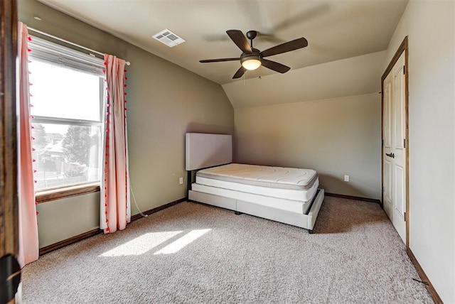 unfurnished bedroom with light colored carpet, vaulted ceiling, and ceiling fan