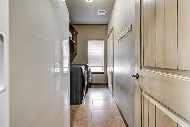 laundry room featuring cabinets, light tile patterned flooring, and washing machine and dryer