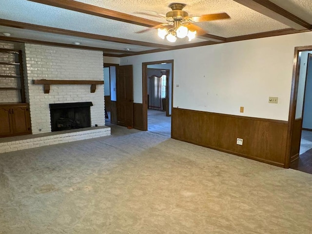 unfurnished living room with a textured ceiling, light colored carpet, ceiling fan, a fireplace, and wood walls