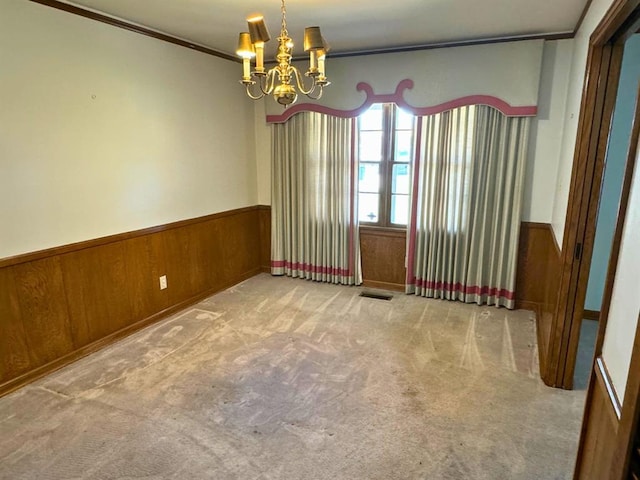 carpeted empty room with ornamental molding, wooden walls, and a chandelier