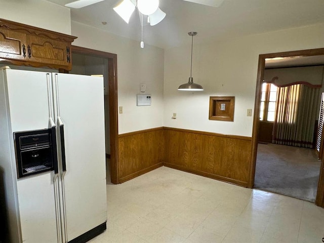 kitchen featuring white refrigerator with ice dispenser, decorative light fixtures, ceiling fan, and wooden walls