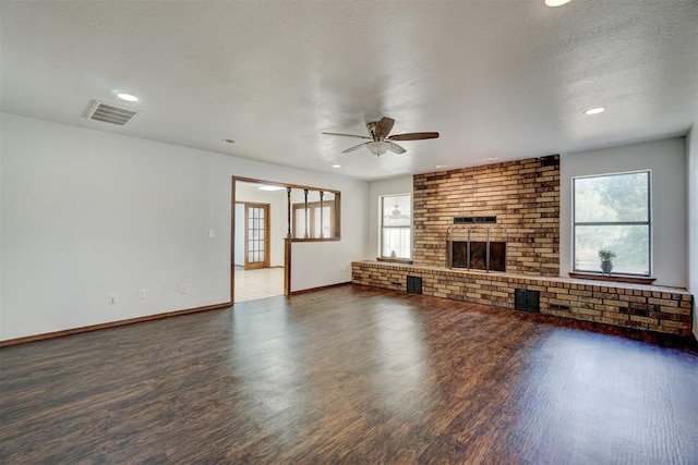 unfurnished living room featuring a fireplace, ceiling fan, dark hardwood / wood-style flooring, and a textured ceiling