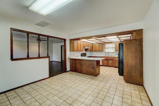 kitchen with black appliances, light tile patterned flooring, kitchen peninsula, and sink