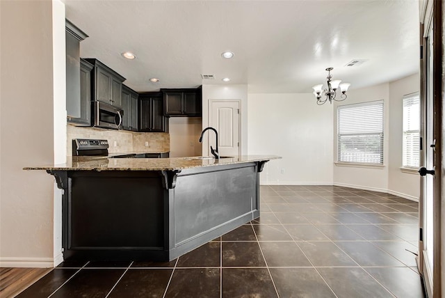 kitchen with sink, an inviting chandelier, light stone counters, a kitchen bar, and appliances with stainless steel finishes