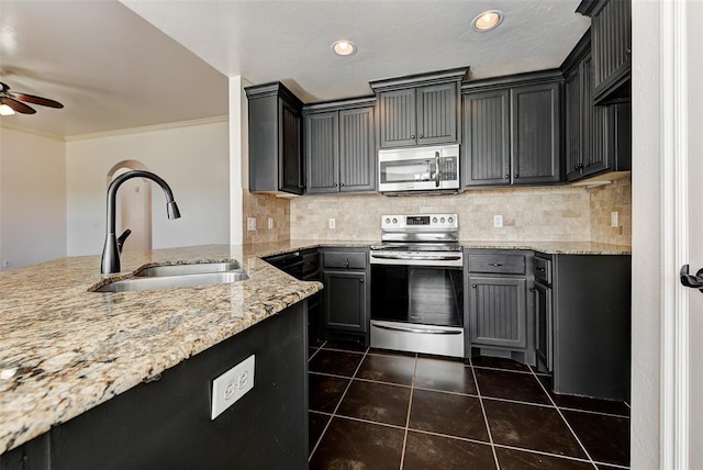 kitchen with light stone counters, sink, dark tile patterned floors, and appliances with stainless steel finishes