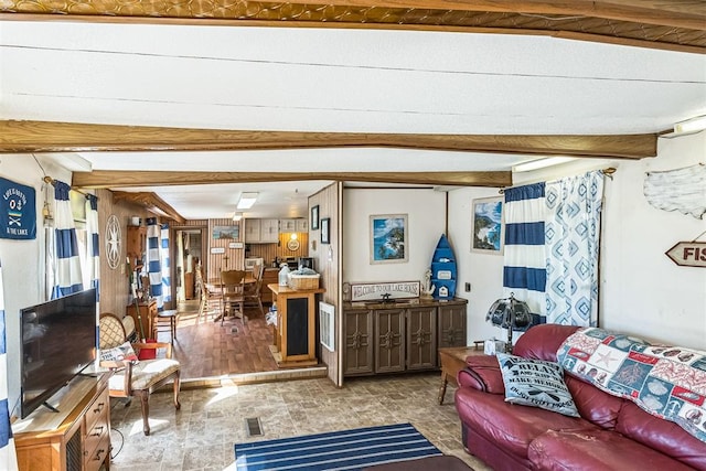 living room with beamed ceiling, light hardwood / wood-style flooring, and wooden walls