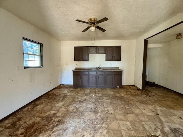 kitchen with dark brown cabinetry, ceiling fan, sink, and a textured ceiling