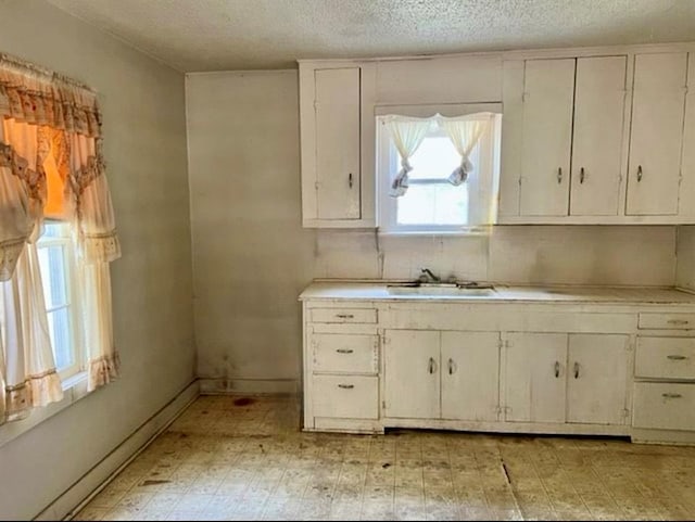 kitchen with white cabinets, a textured ceiling, and sink