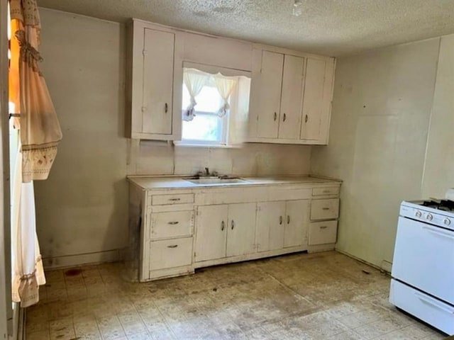 kitchen with white cabinetry, sink, and white gas range oven