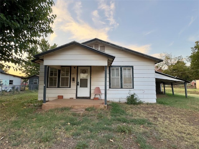 bungalow-style home with a lawn and a carport