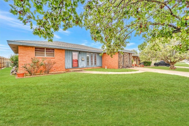 ranch-style house featuring a front yard, fence, concrete driveway, and brick siding