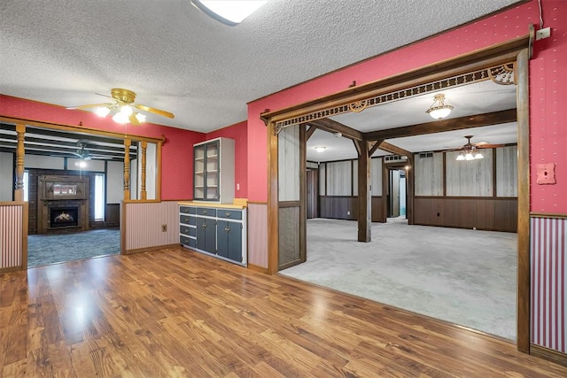 kitchen featuring a ceiling fan, a wainscoted wall, and wood finished floors