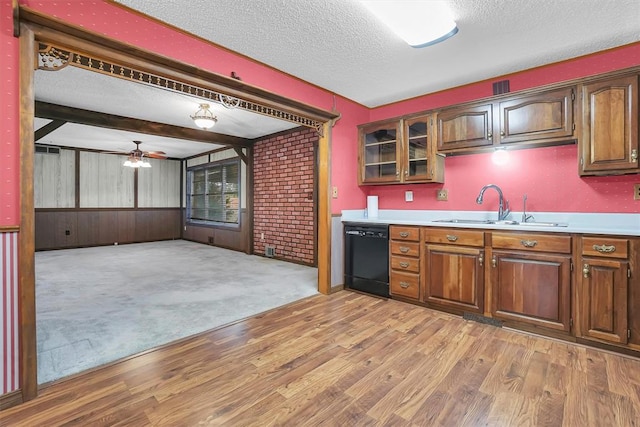 kitchen featuring light wood finished floors, black dishwasher, light countertops, a textured ceiling, and a sink