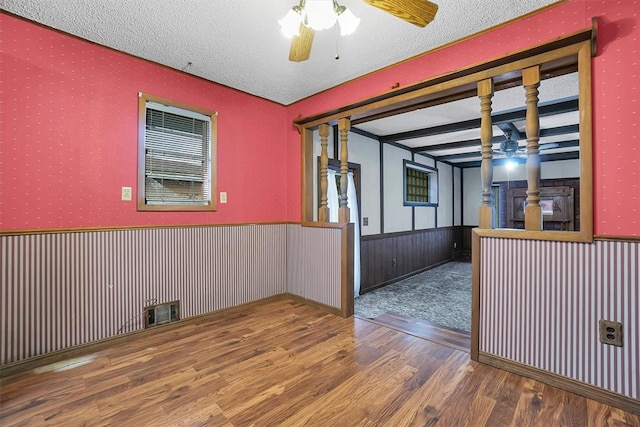 unfurnished room with a ceiling fan, wainscoting, wallpapered walls, and wood finished floors