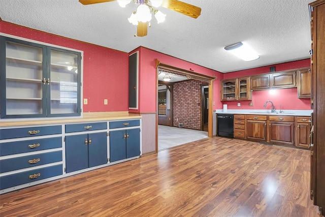 kitchen with dishwasher, glass insert cabinets, wood finished floors, a textured ceiling, and a sink