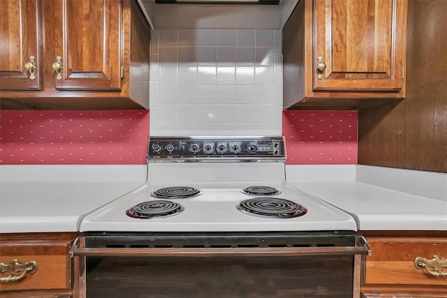 kitchen with tasteful backsplash, brown cabinetry, electric stove, light countertops, and wall chimney range hood