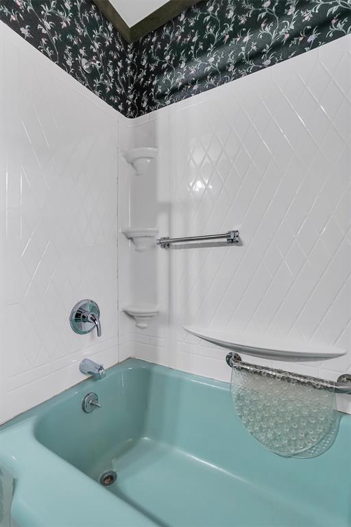 bathroom with shower / bathing tub combination and wallpapered walls