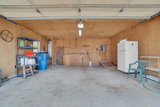 garage with water heater, a garage door opener, freestanding refrigerator, and wooden walls