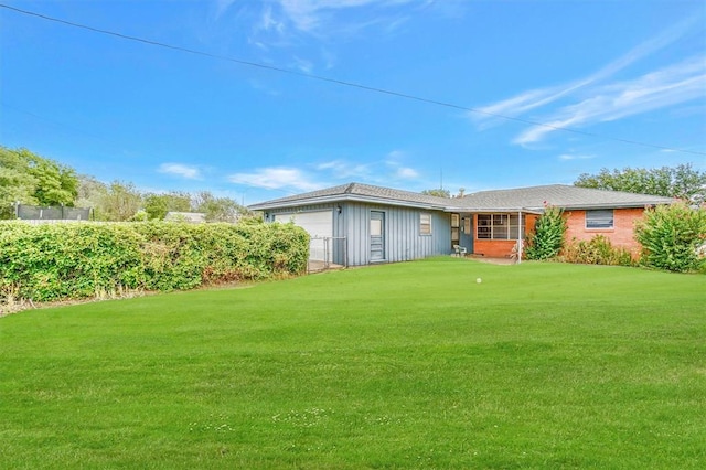 back of property with a garage and a lawn