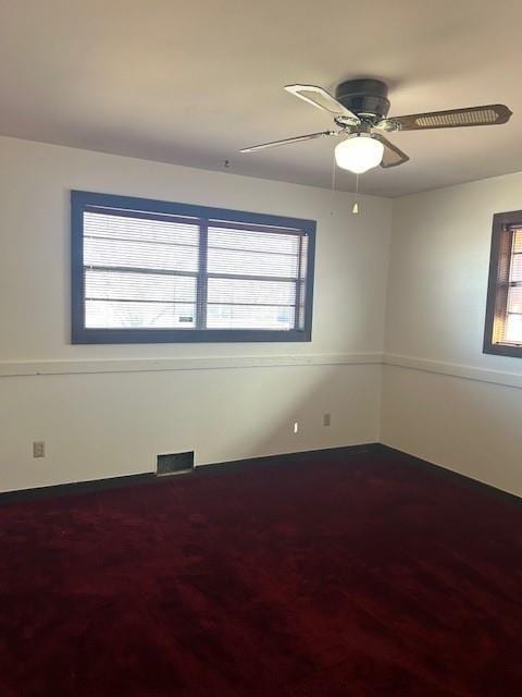 unfurnished room featuring a wealth of natural light, visible vents, and ceiling fan